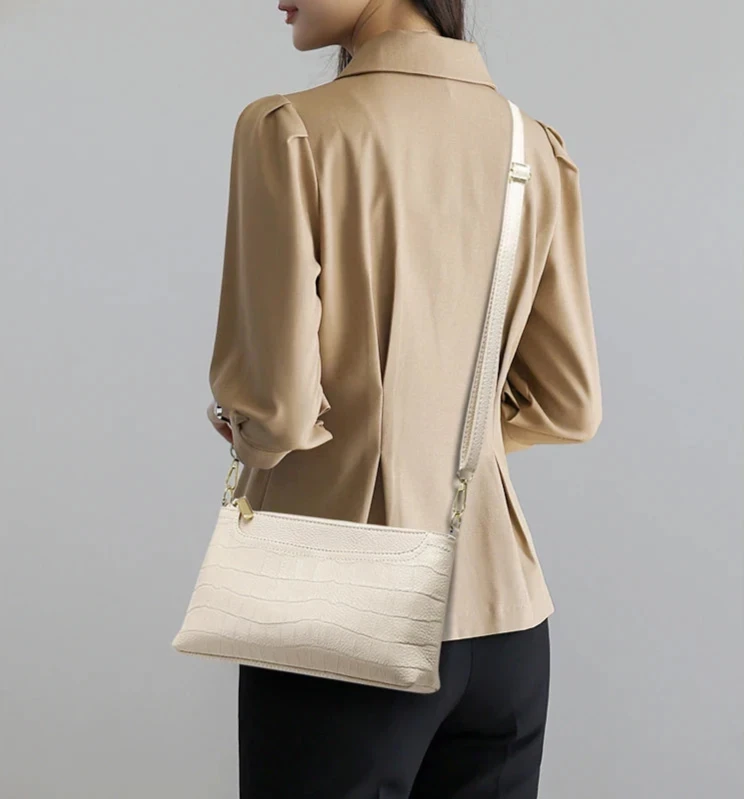 a woman wearing an elegant beige blouse and a beige leather bag, showing a modern and casual look.