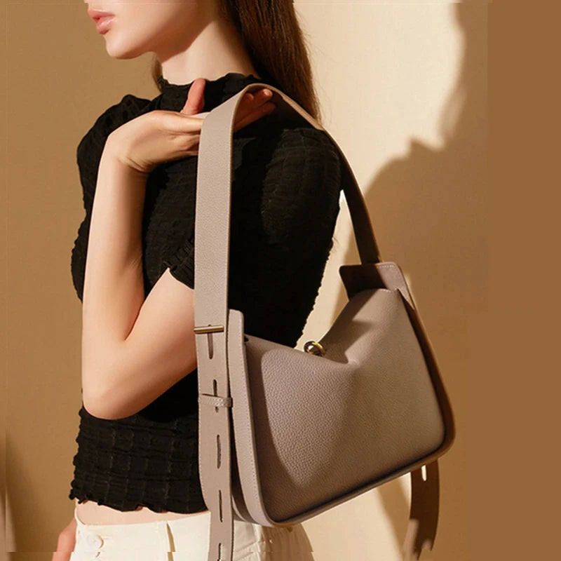 Model holding an elegant designer leather bag with sophisticated finish.