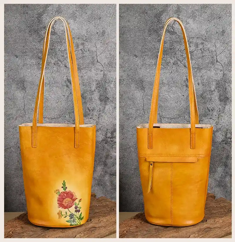 Yellow leather tote bag with artistic design print, with leather handles and back zipped pocket, front and back views.