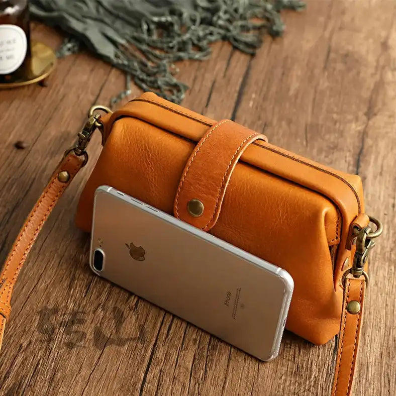 Elegant orange leather shoulder bag with a smartphone, for size reference, front view.