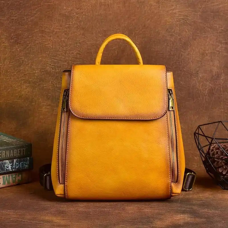 Modern yellow leather bag with zippers and handle, front view.