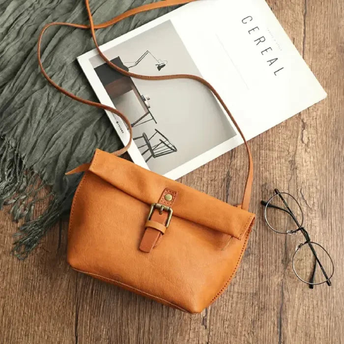 Yellow leather crossbody bag with elegant buckle and long strap, top view.