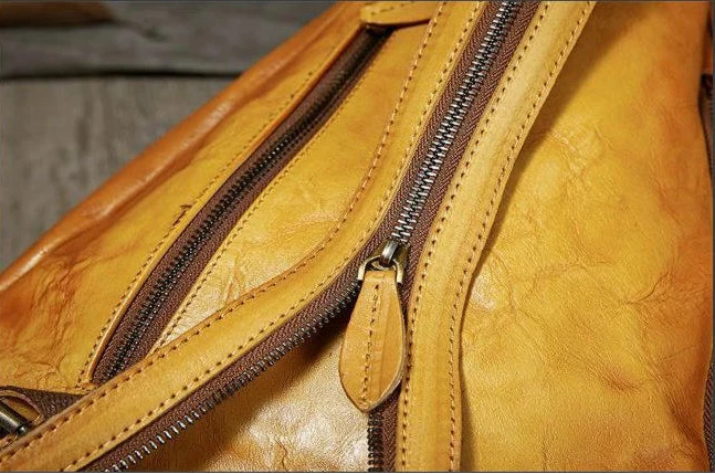 Close-up view of a vintage yellow leather bag with a zipper detail.