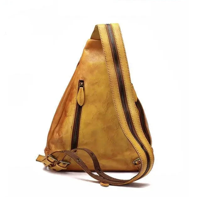 back view of a triangular shaped yellow leather shoulder bag with multiple zippers and a unique strap design.