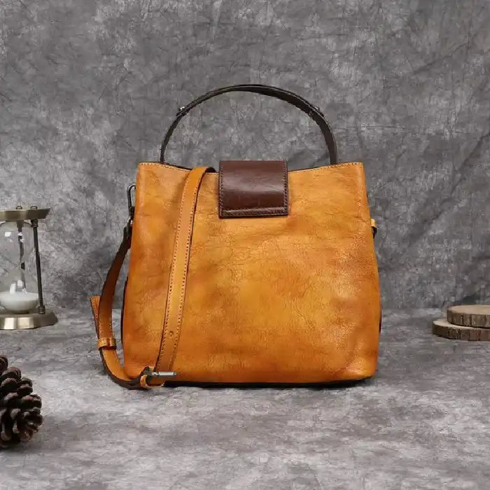 Orange women leather handbag with brown details, soft handle and adjustable strap, back view.