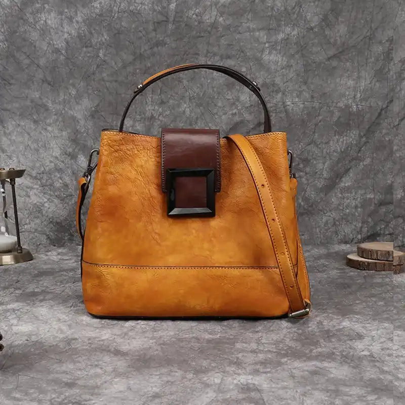 Orange women leather handbag with brown details, soft handle and adjustable strap, front view.